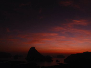 Arka planda dağ olan gün batımının bulanık bir görüntüsü. Gökyüzü karanlık ve güneş batıyor. Huzur ve huzur havası yaratıyor.