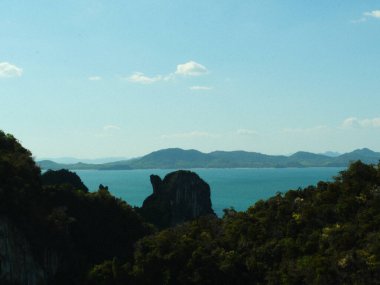 Önünde bir su kütlesi olan bir dağ silsilesinin bulanık görüntüsü. Gökyüzü açık ve su mavi.