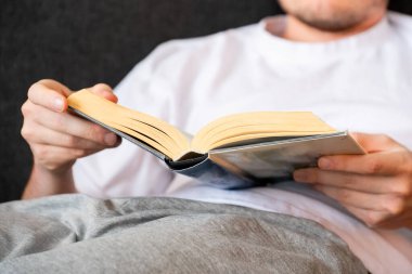 Kanepede oturup kitap okuyan bir adam.