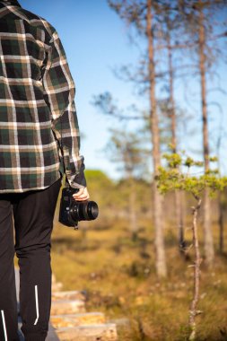 female person walking on duckboards in wetlands with a camera in her hand clipart