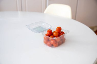 Beyaz mutfak masasındaki pakette biraz kiraz domatesi.