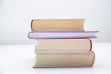 Masanın üzerinde beyaz arkaplanı olan bir yığın kitap