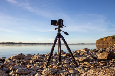 Sahilde tripodun üzerinde profesyonel bir kamera..