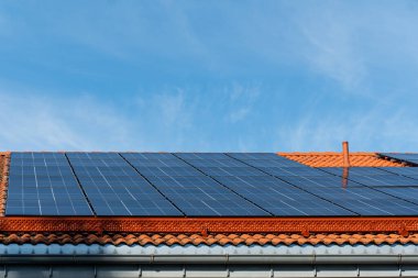 Güneşli bir günde çatıda mavi gökyüzü olan bir grup güneş paneli