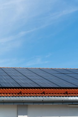 Güneşli bir günde çatıda mavi gökyüzü olan bir grup güneş paneli