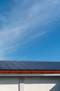 Güneşli bir günde çatıda mavi gökyüzü olan bir grup güneş paneli