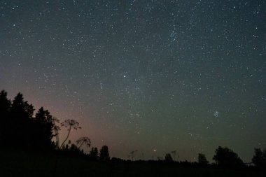 Gece gökyüzü ve yıldızlarla kaplı arazi manzarası