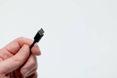 Beyaz zemin üzerinde usb-c kablosu tutan el