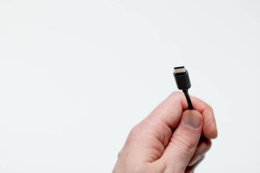Beyaz zemin üzerinde usb-c kablosu tutan el