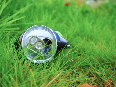 Atılan alüminyum içecekler yeşil çimenlerin üzerinde durabilir. Çevre kirliliğinin ve kirliliğin bir sembolü.