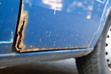 Mavi bir arabanın kapısındaki pas hasarını kapat.