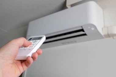 Sıcaklığı ayarlamak için klima uzaktan kumandası kullanılıyor