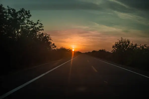 Arkasında günbatımı olan boş yol