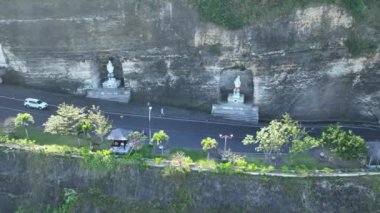 Pandawa Sahili 'nin kayalık yüzeyine inşa edilmiş dini heykellerinin insansız hava aracı görüntüleri. Yoldan geçen arabalar 