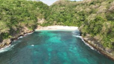 Güzel tropikal ada plajı beyaz kum turkuaz deniz. İnsanlar cennette dinleniyor. Arkadaki yeşil tepeler ve yemyeşil orman. Pandan Plajı Nusa Penida Endonezya Bali. Hava aracı görüntüsü 4K. Dji Maviç 3 videosu 