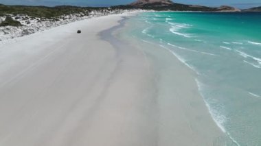 Dörtlü bisiklet beyaz kumsalda sürüyor. Wharton Beach Esperance Avustralya 'da ATV sürücüsü. Beyaz kum turkuaz denizinde dört tekerli motorun hava aracı görüntüleri. 4K