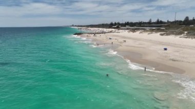 City Beach Perth Avustralya 'nın destansı hava manzarası. Yazın güneşlenen ve denizde yüzen bir sürü insan var. Batı Avustralya kıyı şeridi, insanlar tatilde. Hava aracı görüntüsü 4K. DJI Mavic 3