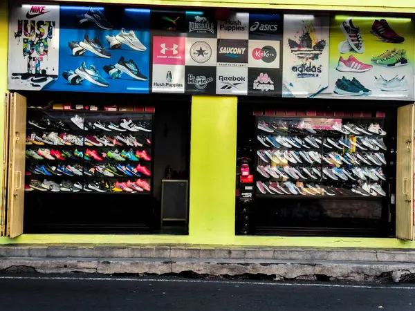 stock image Jawa Tengah, Indonesia - July 31, 2024: Sports shoes and sneakers on display on the rack of a shoe store. Stylish and fashionable branded shoes for sale in a retail store