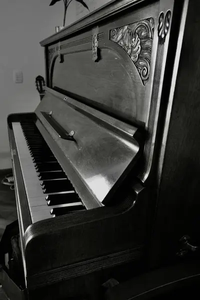 stock image Monochrome image of an antique upright piano, showcasing intricate carved details and keyboard. Perfect for music themes, vintage aesthetics, and artistic interior design concepts.