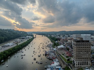 Bu çarpıcı hava fotoğrafı Batı Virginia, Charleston 'daki doğa ve kentsel yaşamın harmanlanmış hallerini yakalar. Teknelerle benekli sakin Kanawha Nehri, bereketli bir arazide hızla ilerler ve hareketli bir şehir manzarasına yol açar. Batan güneş