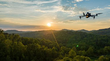 Drone capturing the ethereal beauty of a forest at sunset, with a vibrant sky as the backdrop. clipart