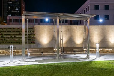Park 'taki ışıklı bankta salıncaklar Gazeebo tarafından korunuyor.