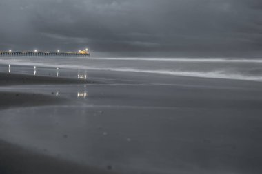 Gece Sahil ve İskelesi: Sakin Su Üzerine Aydınlanmış Yansımalar