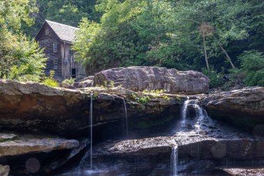 Glade Creek Grist Mill, Babcock Eyalet Ormanı 'nda çağlayan bir şelalenin ve yemyeşil yeşilliğin ortasında duruyor..