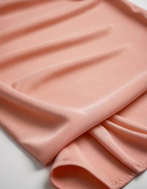 Soft silky fabric in a delicate peach tone with elegant draping folds. clipart