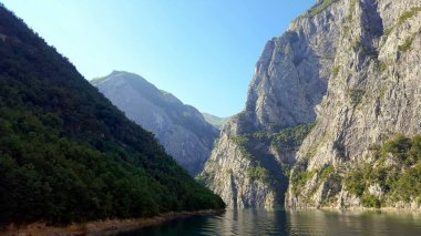 ALBANIA.Lake Koman, Arnavutluk 'un kuzeyindeki Drin Nehri' nde, sık ormanlık tepeler, dikey yamaçlar, derin vadiler ve dar bir vadiyle çevrili bir rezervuar.