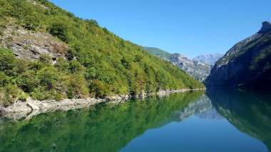 ALBANIA.Lake Koman, Arnavutluk 'un kuzeyindeki Drin Nehri' nde, sık ormanlık tepeler, dikey yamaçlar, derin vadiler ve dar bir vadiyle çevrili bir rezervuar.