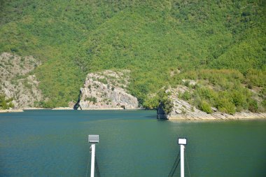 ALBANIA.Lake Koman, Arnavutluk 'un kuzeyindeki Drin Nehri' nde, sık ormanlık tepeler, dikey yamaçlar, derin vadiler ve dar bir vadiyle çevrili bir rezervuar.