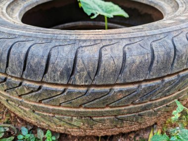 Close-up of the surface texture of a used car tire that is no longer in use, lying on the ground. clipart