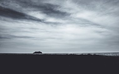 Kara, kayalık kıyı şeritleri kara kara kara bir okyanusun altında, bulutlu bir gökyüzünün altında dramatik ve karamsar bir deniz manzarası yaratarak Tayland 'da yalnızlık ve gizemi çağrıştırıyor, Chumphon