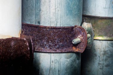Paslı metal kelepçe, galvanize çelik boruları bir araya getirerek, aşınmanın etkilerini ve endüstriyel ortamlardaki bakımın önemini vurguluyor