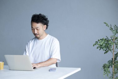 Ofiste dizüstü bilgisayar kullanan genç bir Asyalı.