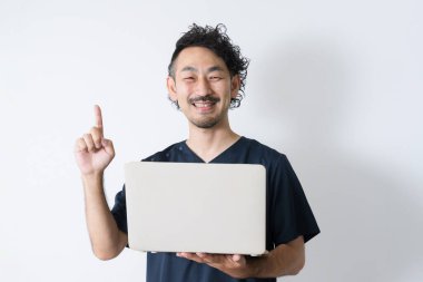Genç Asyalı iş adamı bir fikir jesti olarak parmağını kaldırıyor, dizüstü bilgisayarını tutuyor ve beyaz arka planda poz veriyor.