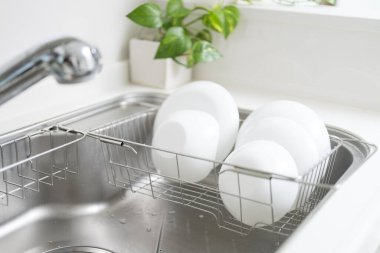 Modern mutfakta lavabonun üzerinde beyaz tabaklar kuruyor.