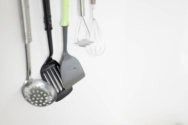 kitchen utensils hanging on white background