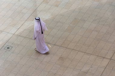 Emirati 'nin yüksek açılı görüntüsü. Kandora giymiş bir adam Dubai Alışveriş Merkezi' nde yürüyor..