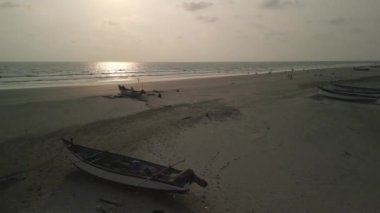 Birkaç balıkçı teknesi kumun üzerinde duruyor. Ve insanlar Hint Okyanusunda yüzerler. Çekimler Goa 'da Hindistan' da