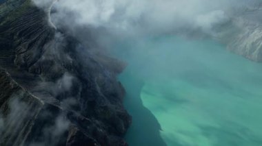 Şafak vakti Kawah Ijen yanardağının turkuaz sülfür gölünün drone görüntüsü. Java, Endonezya 'nın panoramik manzarası. Volkanın arkasında muhteşem bir dağ ve orman manzarası görebilirsiniz..