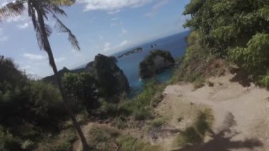 Nusa Penida adasındaki bir ağaç evin yanında uçan bir FPV dronu, bir uçurumdan atlıyor ve adanın tamamında uçuyor.