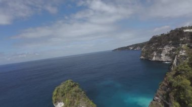 Adalar arasında uçan dron, hızla huş ağacından okyanusa iner. Okyanus manzarası ve Bali 'nin yanındaki Endonezya adası - Nusa Penida