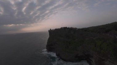 FPV İHA 'sı Bali adasındaki uçurumlardan Uluwatu tapınağına uçuyor. Dalgalar kayalara çarpıyor..