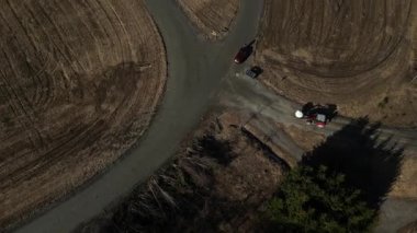 Kırmızı bir traktörle tarımsal topraklar üzerinde uçuyorlar.