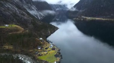 İnsansız hava aracından Norveç fiyordunun eşsiz görüntüsü. Lysfjord 'un aynaya benzeyen yüzeyi, yeşil çayırlar, el değmemiş dağlar ve kalın sis.