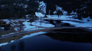 Norveç 'in karlı genişliğini gören bir kuş bakışı. Ördekler neredeyse erimiş bir gölde yüzerler.