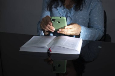 Kitap okuyan akıllı telefon kullanan kadın