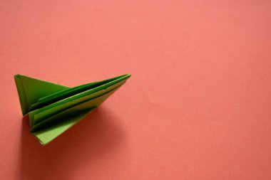 Pembe arka planda yeşil origami kağıt tekne. en üstteki görünüm